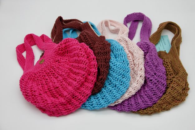 Bunte gehäkelte Handtaschen in verschiedenen Farben, angeordnet in einer Reihe.